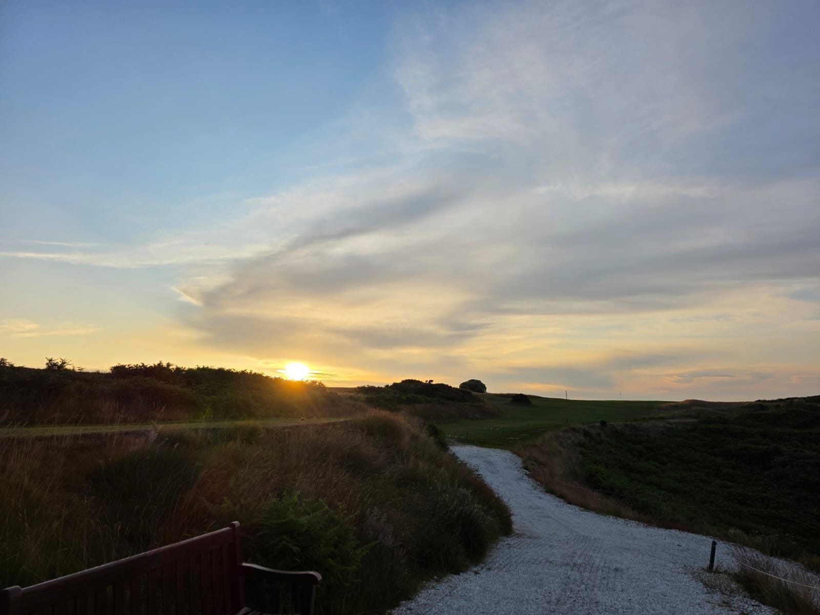 Golfer silhouettes against a dramatic sunset sky